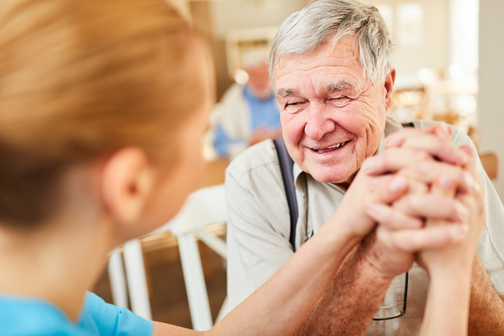 old man holding nurse's hand