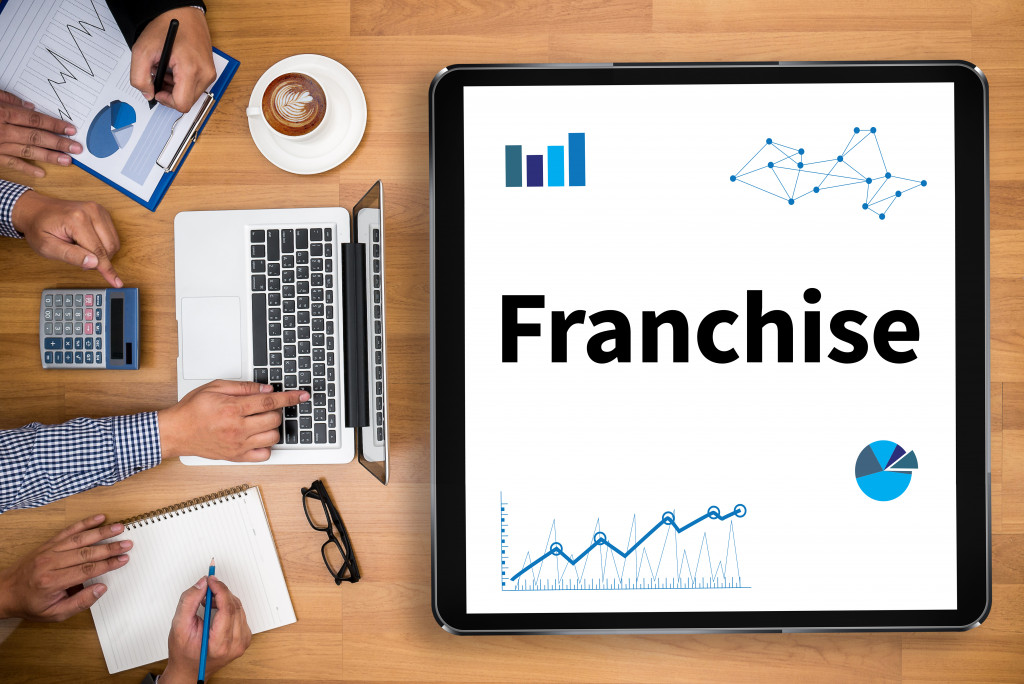 Franchise Business team hands at work with financial reports and a laptop